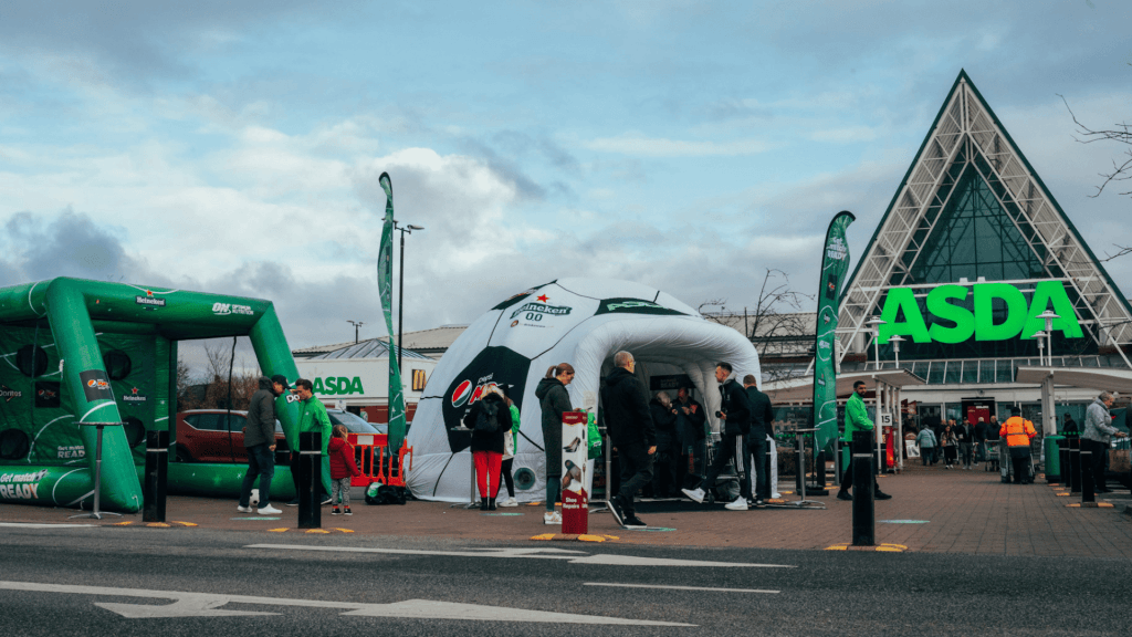 Branded Inflatable Event Structure - Inflatable Dome designed to look like a football alongside a inflatable goal post 